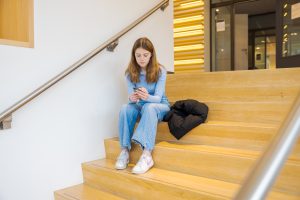 meisje op trap met mobiel in haar hand